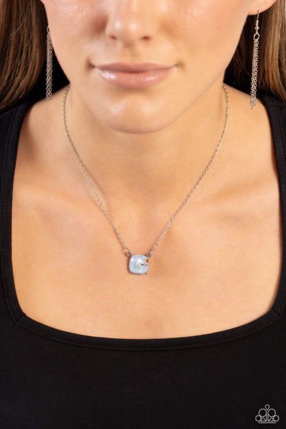 Necklace with a pendant worn by a person against a black background