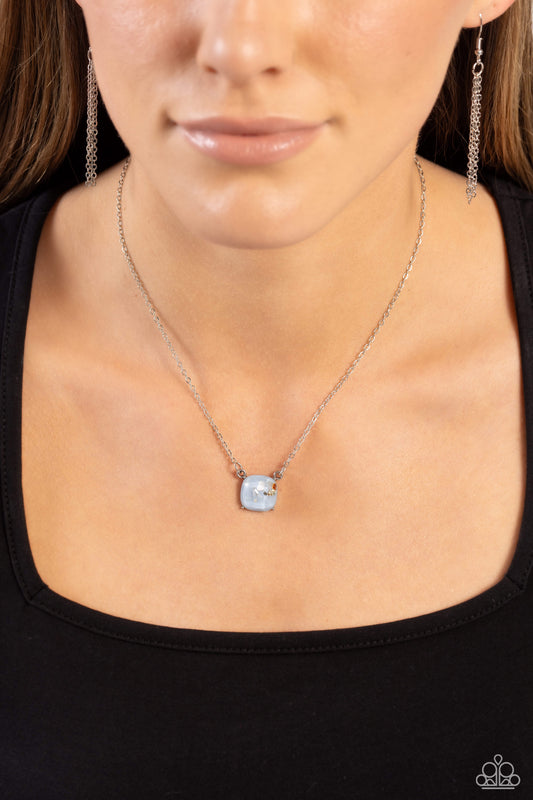 Necklace with a pendant worn by a person against a black background