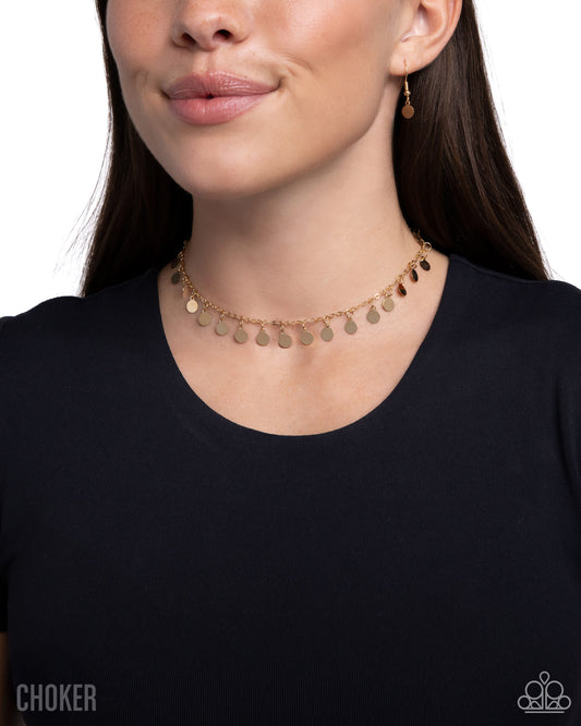 A close-up of a woman wearing a delicate gold disc charm necklace and a matching small drop earring, paired with a black top against a white background. The Choker brand logo is visible in the bottom left corner.