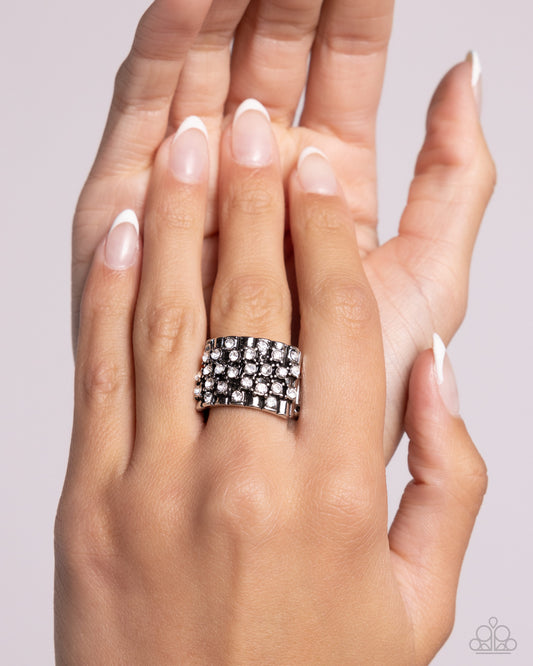 Hand wearing a silver ring with a textured band on a light gray background