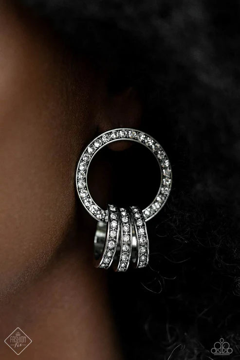 Silver ring earring with multiple loops worn on an ear against a dark background