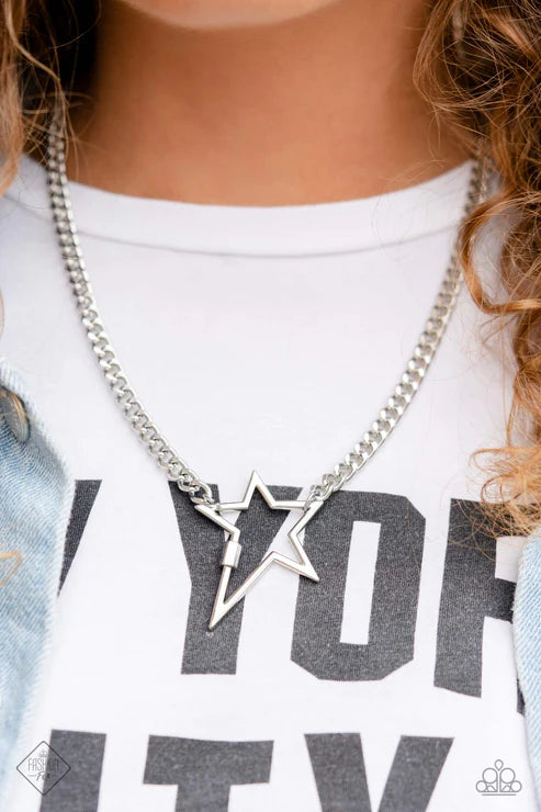 Silver star necklace worn by a person on a white shirt with text