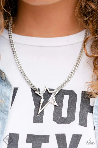 Silver star necklace worn by a person on a white shirt with text