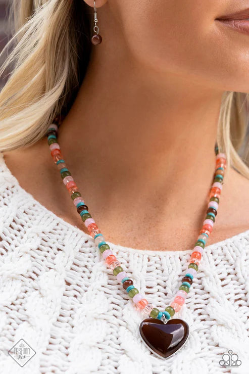 Necklace with a heart-shaped pendant worn by a person on a white background