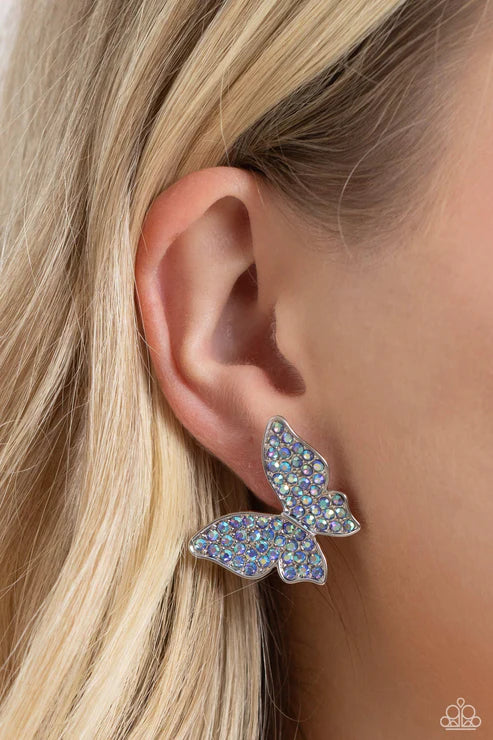 Butterfly-shaped earring worn on a person's ear with blonde hair.