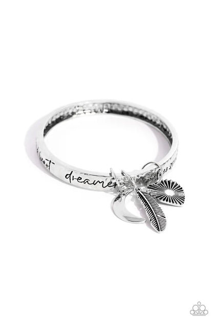 Silver ring with feather charm and 'just dreamer' text on a white background