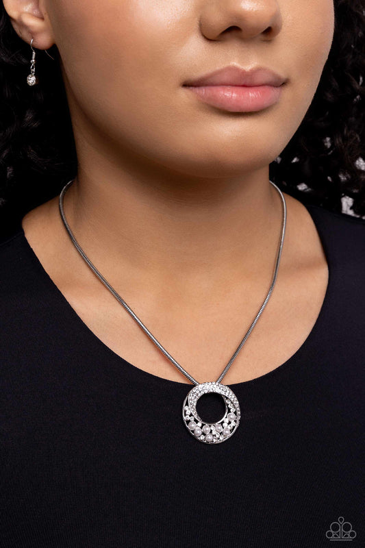Necklace with a circular pendant worn by a person against a dark background