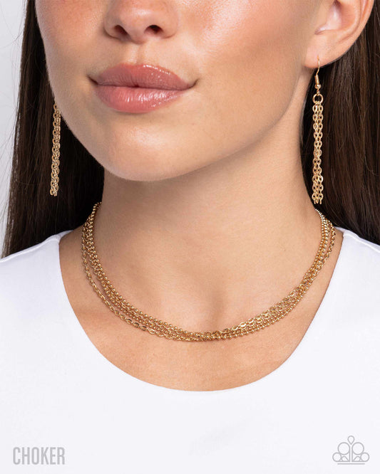 Close-up of a woman wearing a gold chain necklace and earrings on a white background
