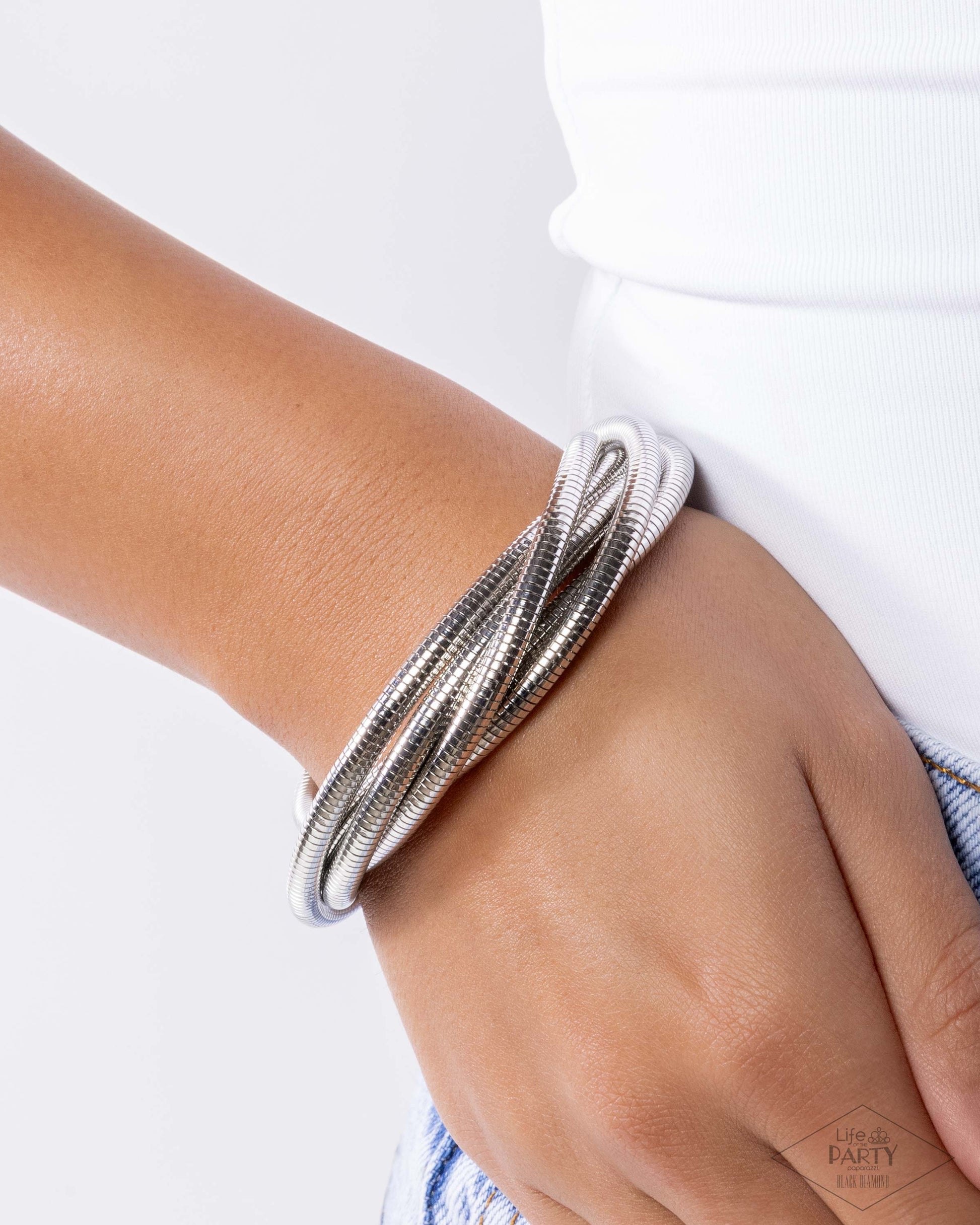 Silver bracelet on a wrist with a white background