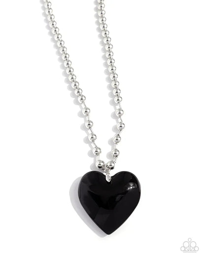 Black heart pendant on a silver chain against a white background
