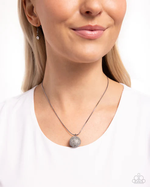 Woman wearing a silver necklace with a textured pendant on a white background