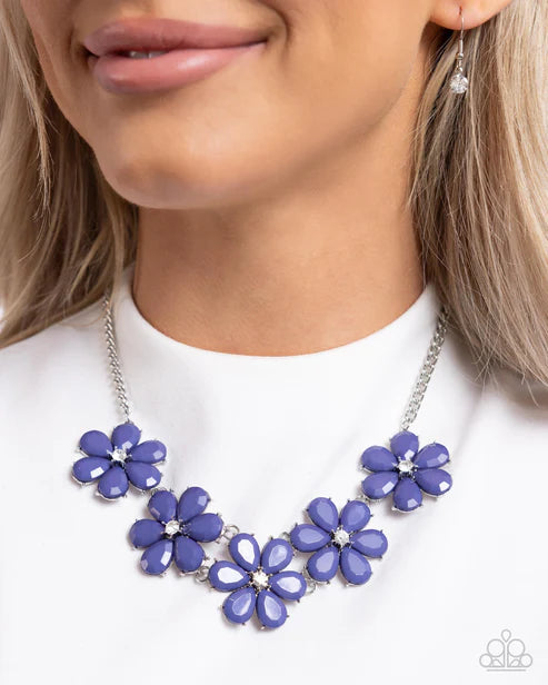 Blue floral necklace worn by a model on a white background
