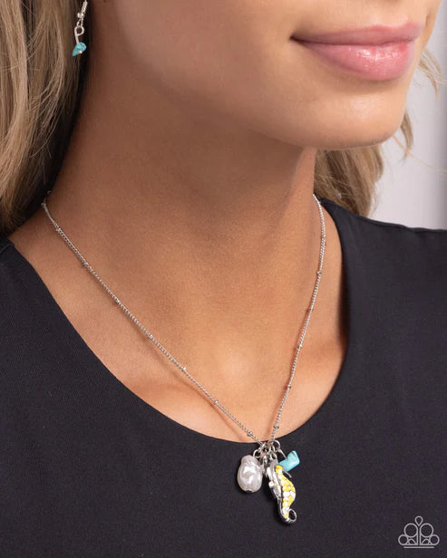 Necklace with seahorse charm worn by a person against a neutral background