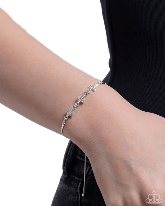 Silver bracelet on a wrist with a plain background