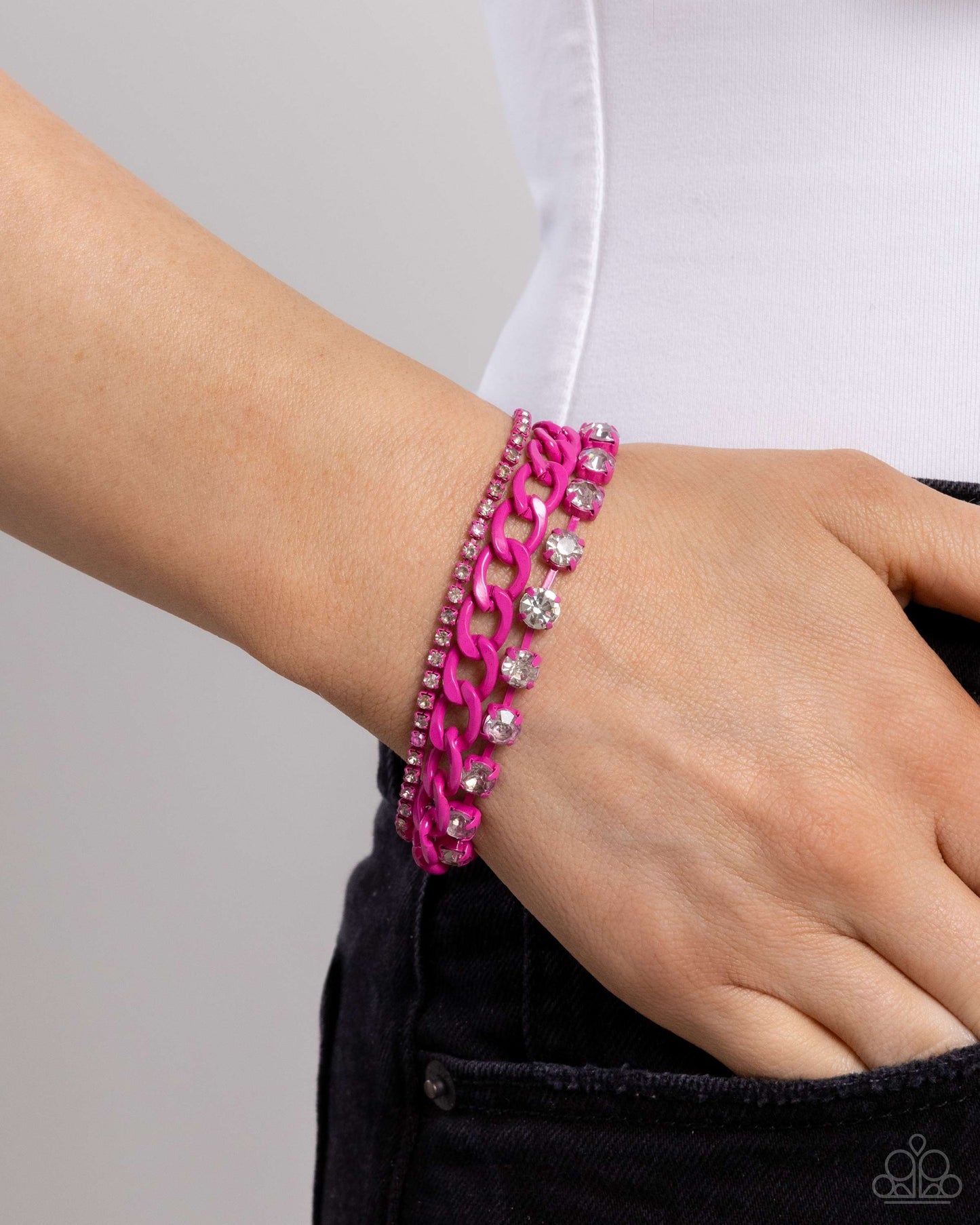 Pink chain bracelet on a wrist with a plain background