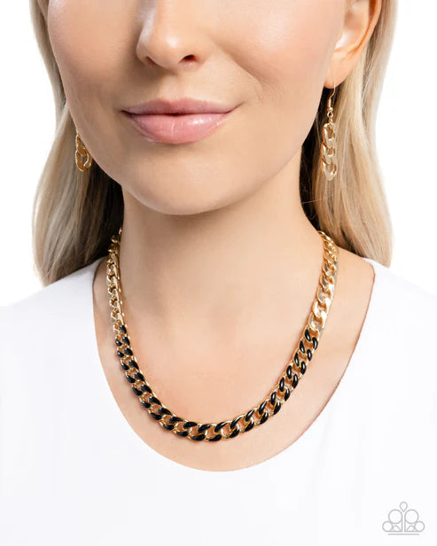 Close-up of a person wearing a gold and black chain necklace on a white background