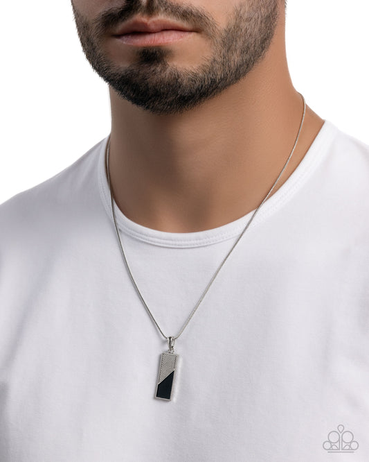 Man wearing a silver necklace with a black pendant on a white background