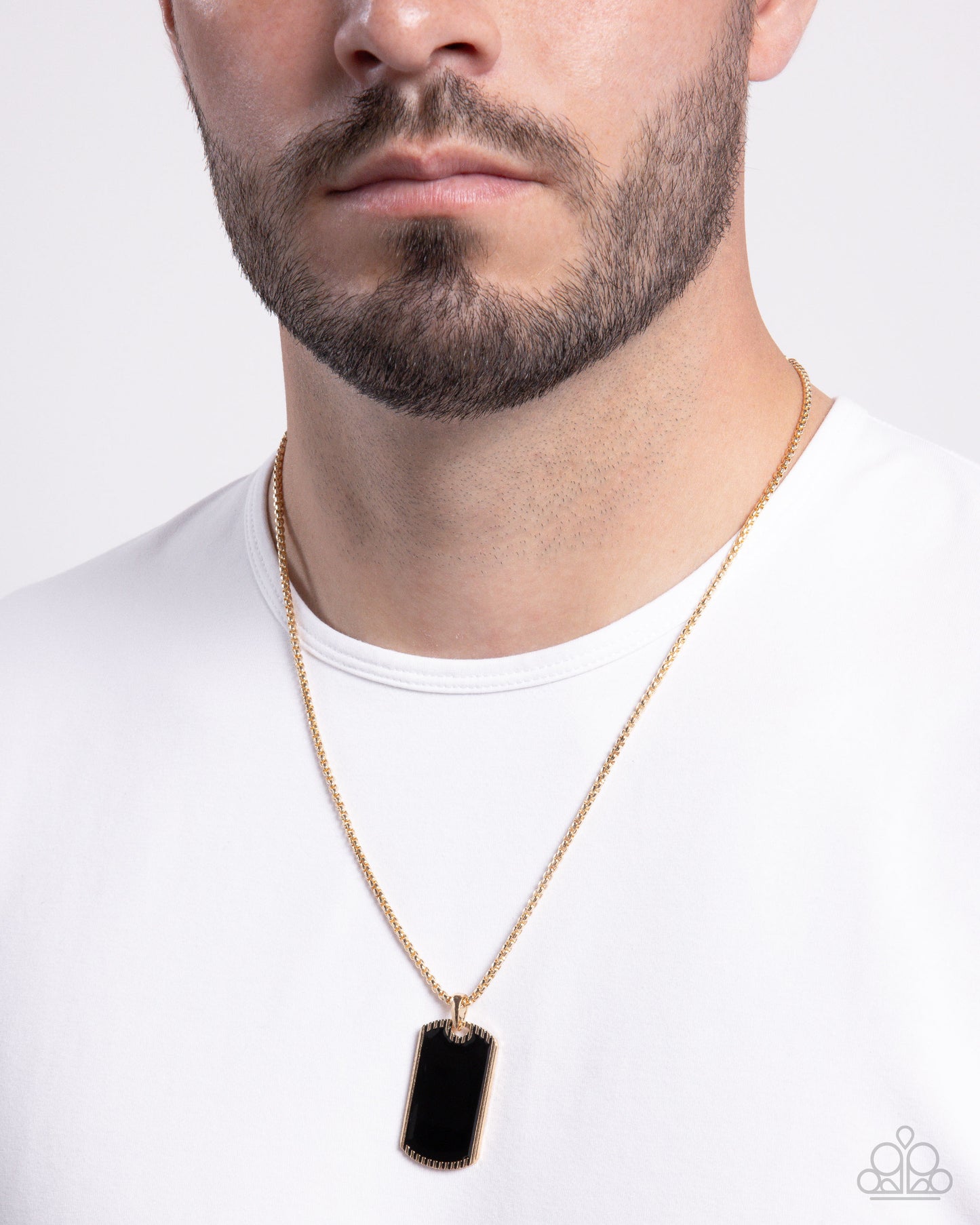 Man wearing a gold necklace with a black pendant on a white background