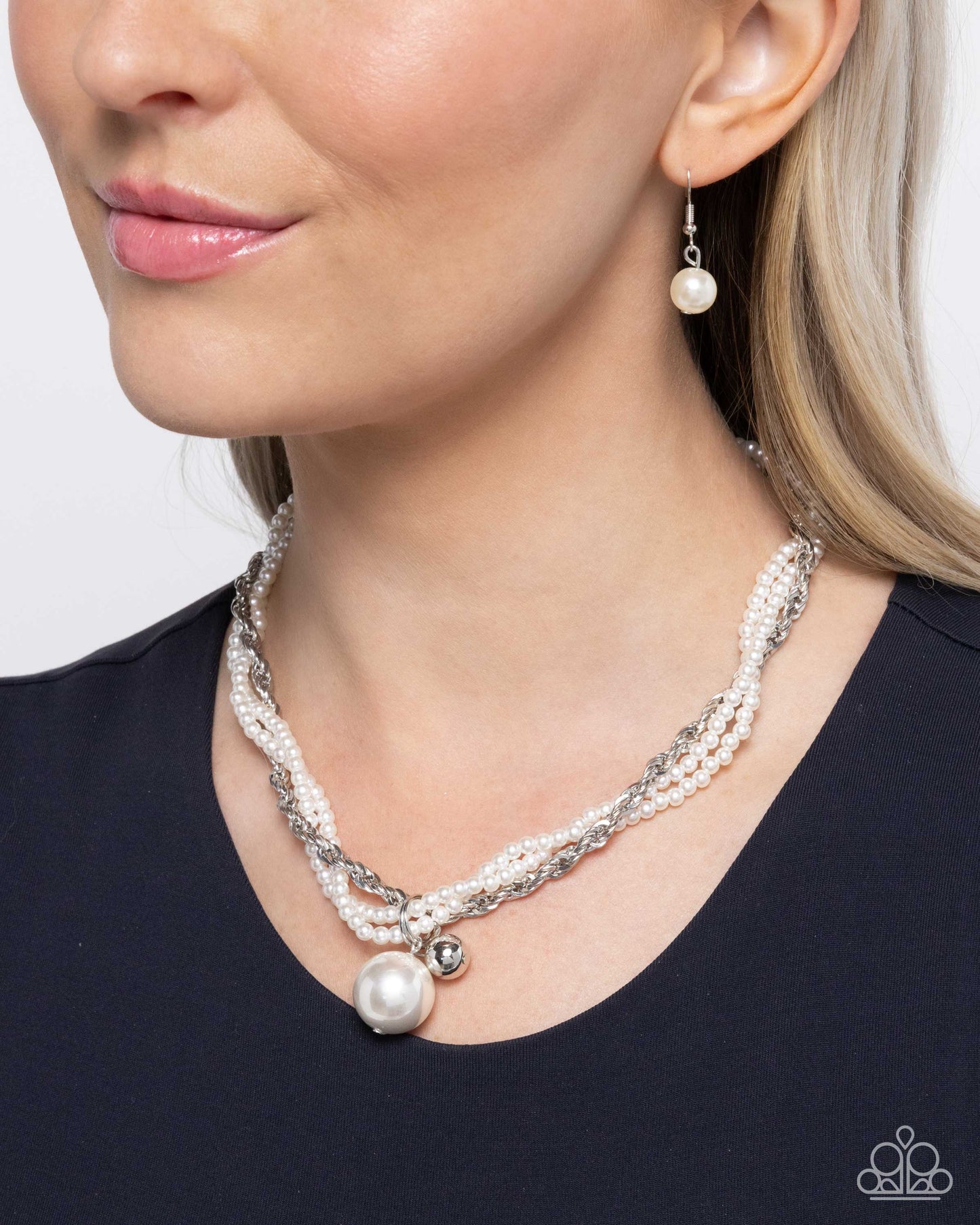 Close-up of a woman wearing a pearl necklace and earrings on a plain background