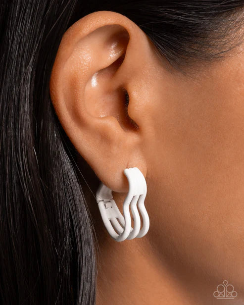 Close-up of an ear wearing a white earring with a blurred background
