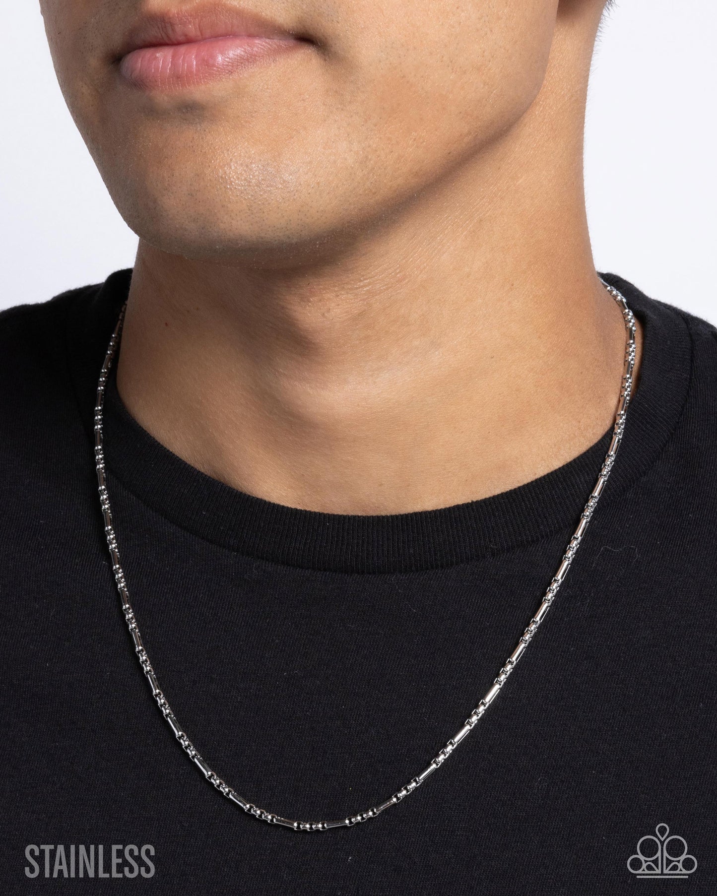 Person wearing a silver chain necklace against a plain background
