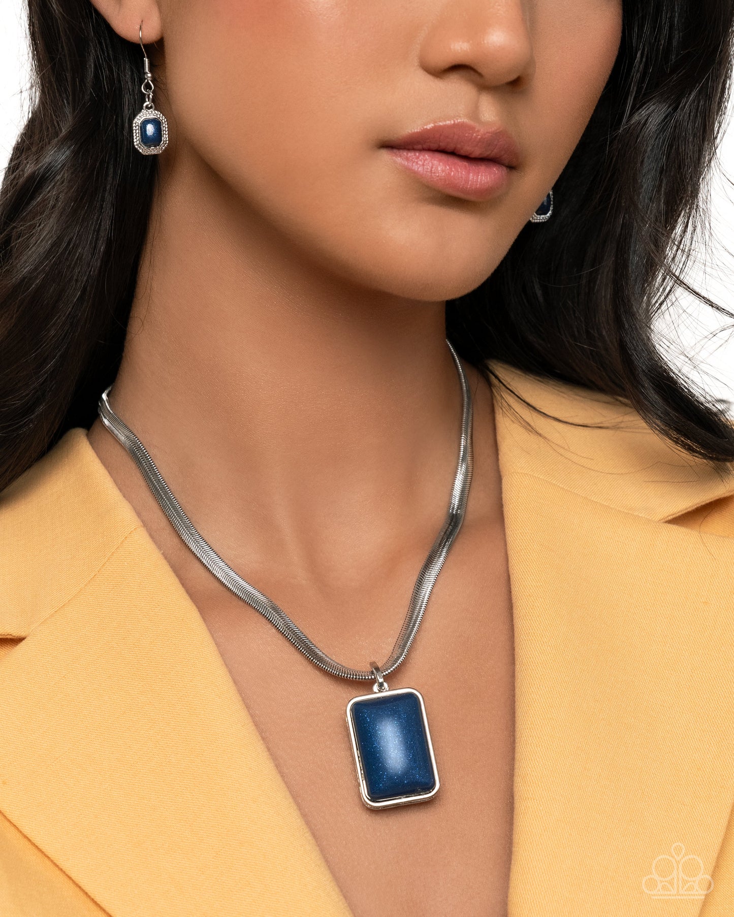 Close-up of a woman wearing a silver necklace with a blue pendant and matching earrings.