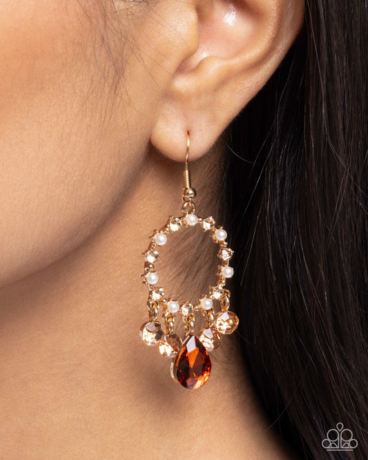 Close-up of an earring with a teardrop-shaped gemstone worn by a person.
