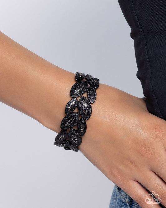 Black lace bracelet on a wrist against a light gray background
