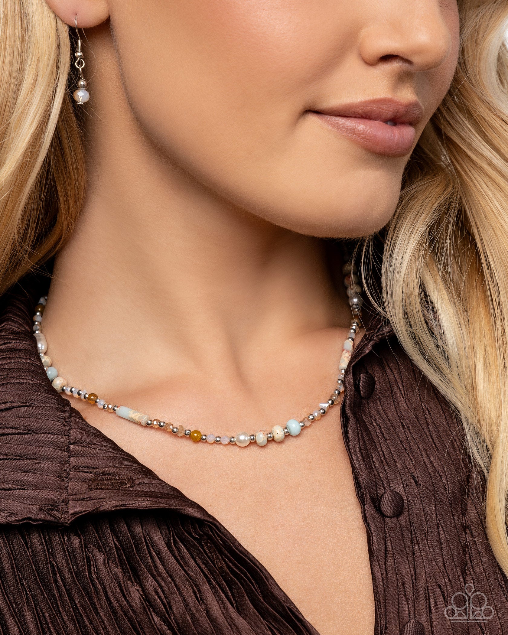 Close-up of a woman wearing a beaded necklace and earrings.