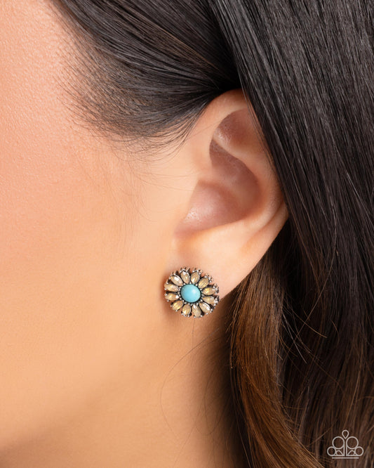 Close-up of an ear wearing a floral earring with a turquoise center.