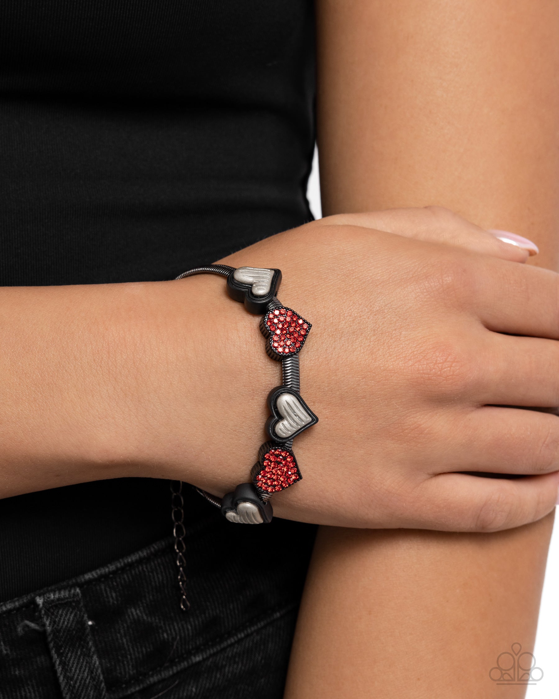 Bracelet with red heart-shaped beads on a wrist against a neutral background