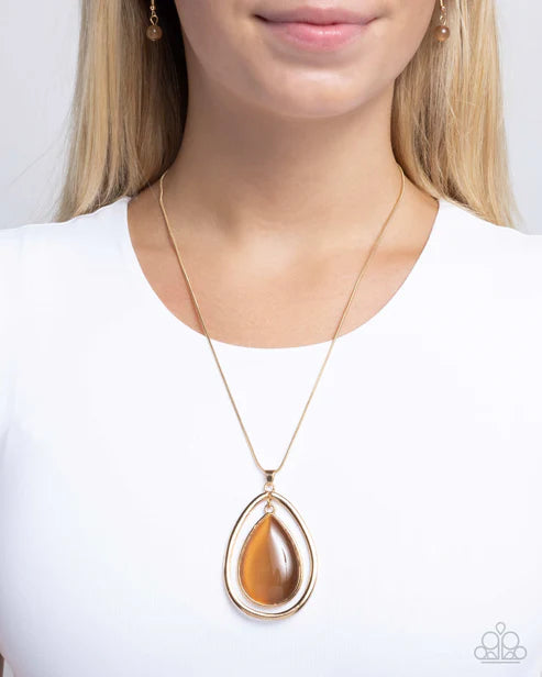 Necklace with a teardrop-shaped brown pendant worn by a person on a white background
