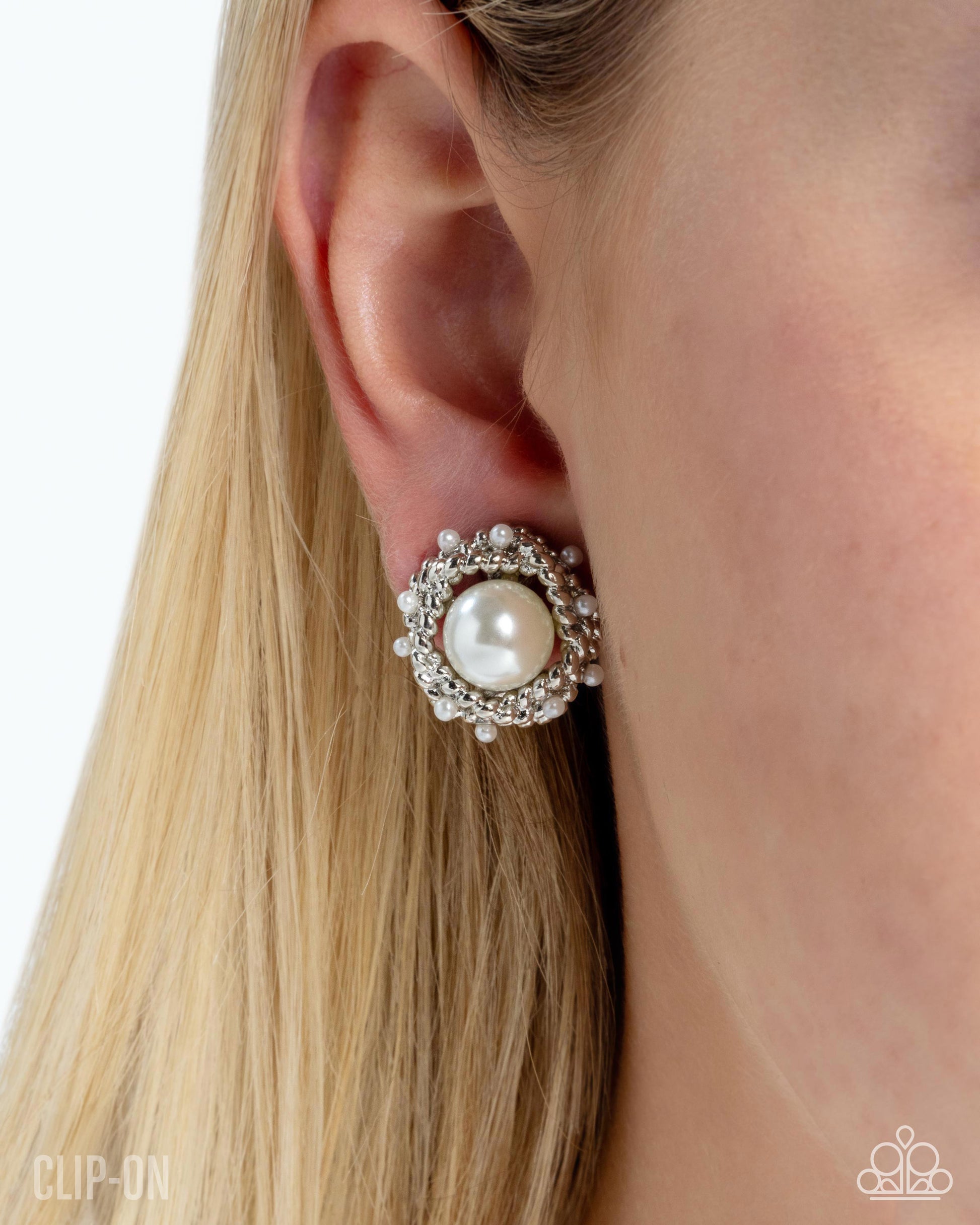 Close-up of an ear wearing a decorative earring with a pearl center.