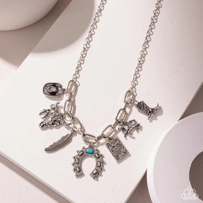 Silver necklace with various charms on a white surface