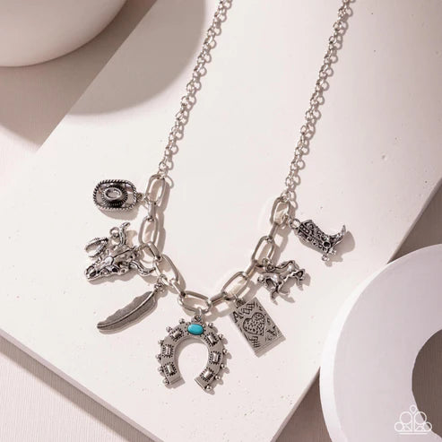Silver necklace with various charms on a white surface