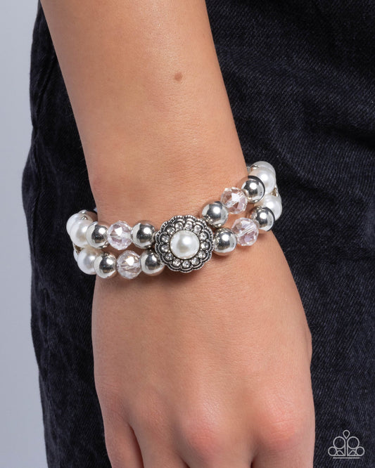 Bracelet with pearls and silver beads on a wrist against a dark background