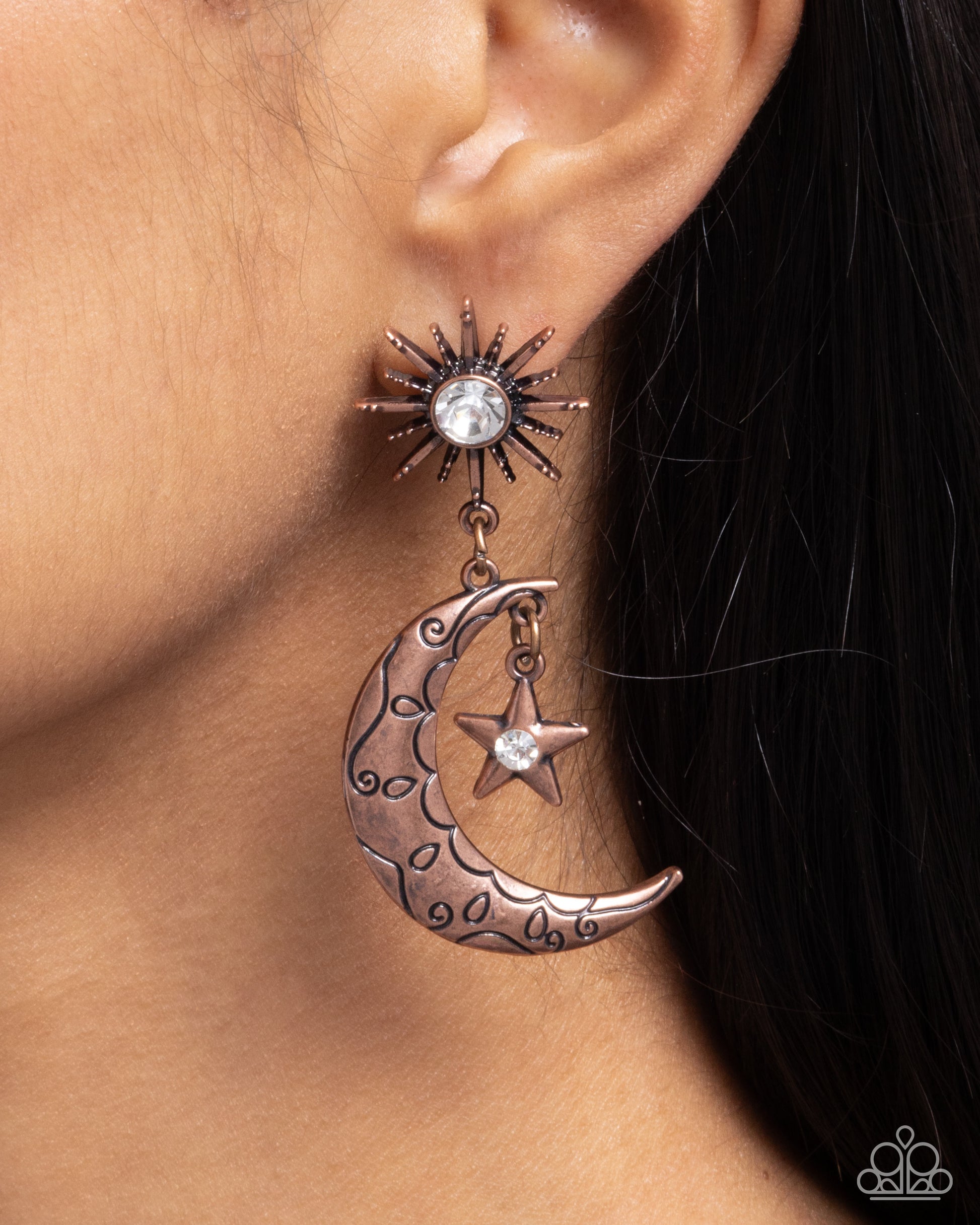 Earring with sun, moon, and star design on a person's ear