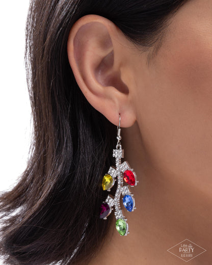 Close-up of an ear wearing a colorful gemstone earring with a blurred background