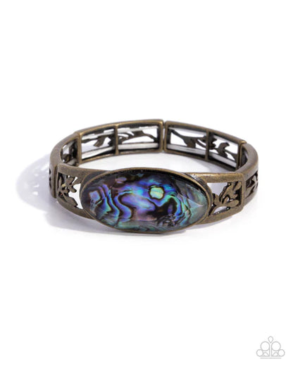 Brass bracelet with abalone shell center on a white background