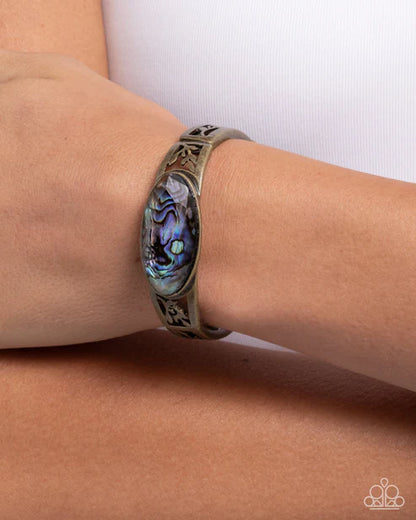 Bracelet with abalone shell design on a wrist against a white background