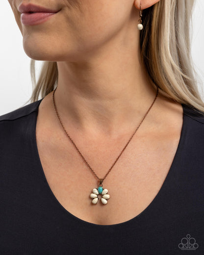 Necklace with a flower pendant worn by a person against a neutral background