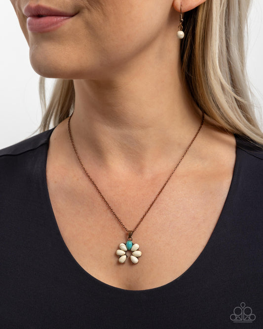 Necklace with a flower pendant worn by a person against a neutral background