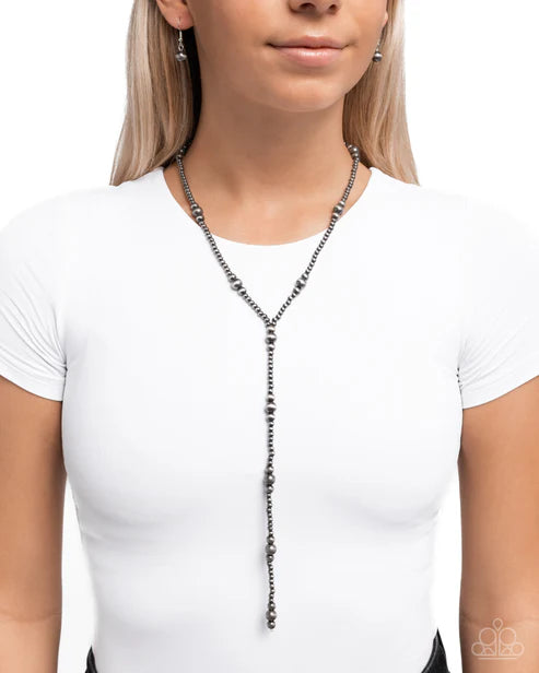 Woman wearing a long necklace against a white background