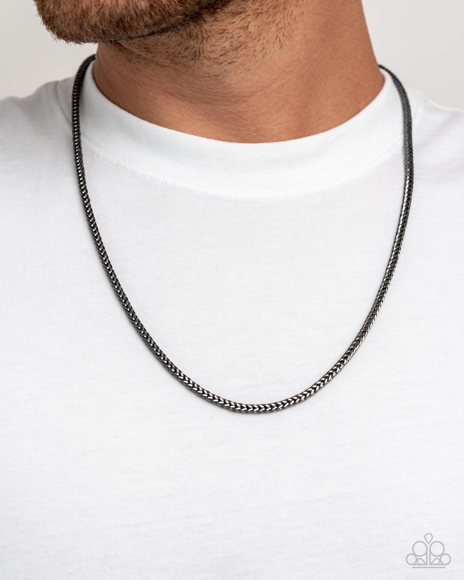 Black chain necklace worn by a person on a white background