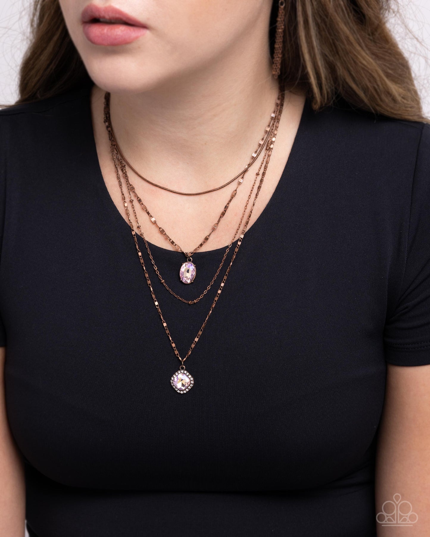 Layered necklaces on a person wearing a black top against a neutral background