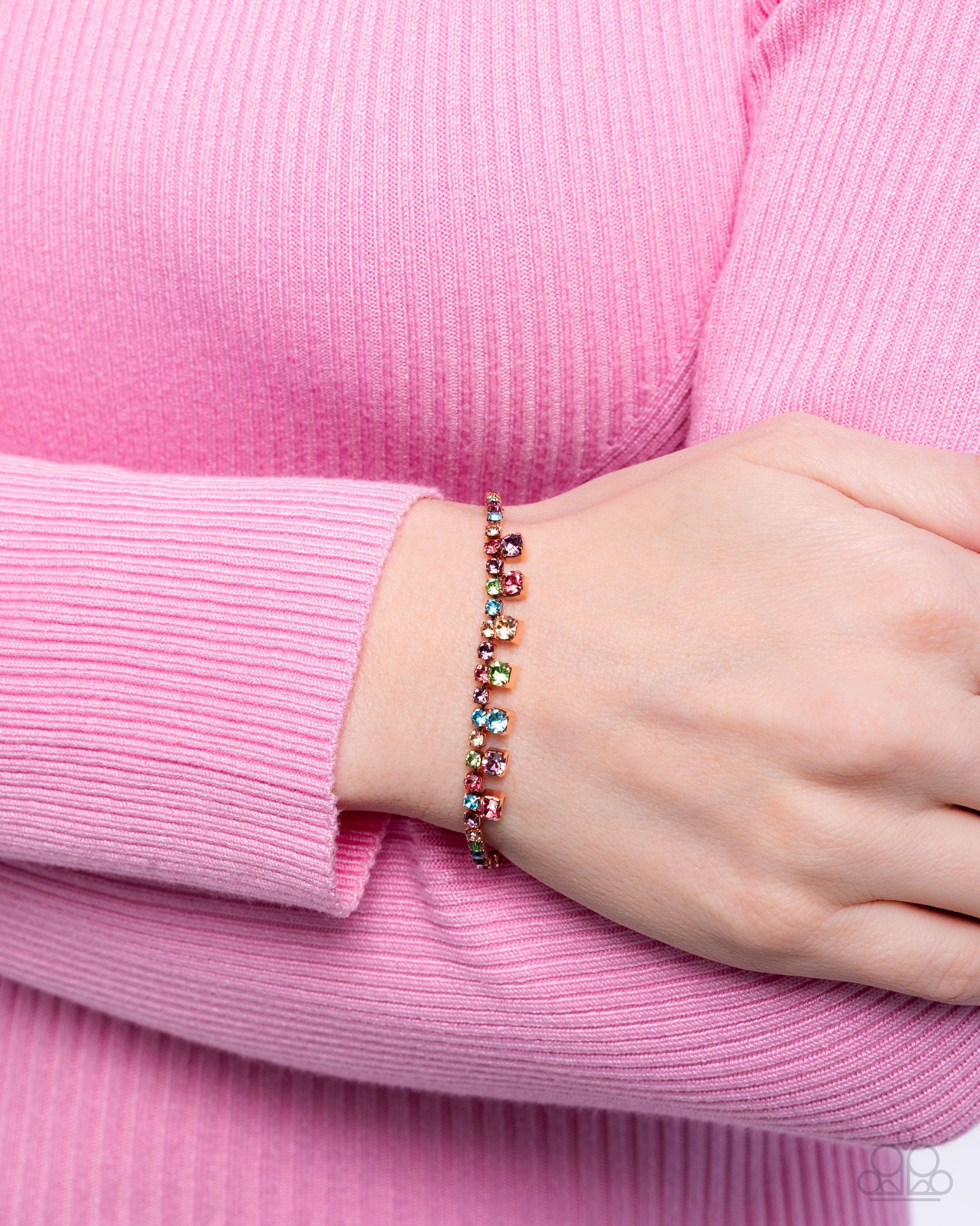 Multicolored beaded bracelet on a wrist with a pink sweater
