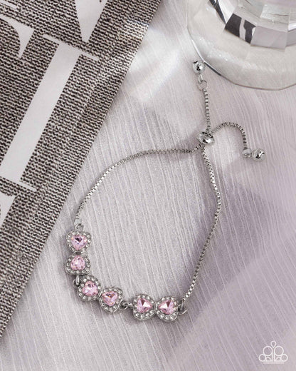 Silver bracelet with pink gemstones on a textured surface