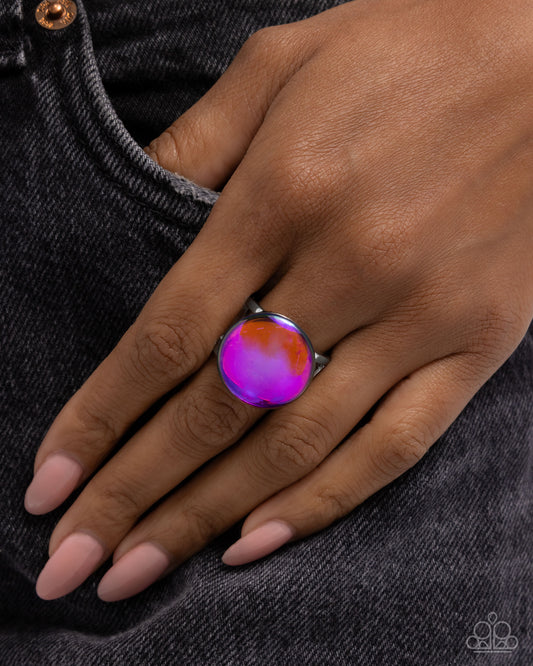 Hand wearing a colorful ring on a dark denim background