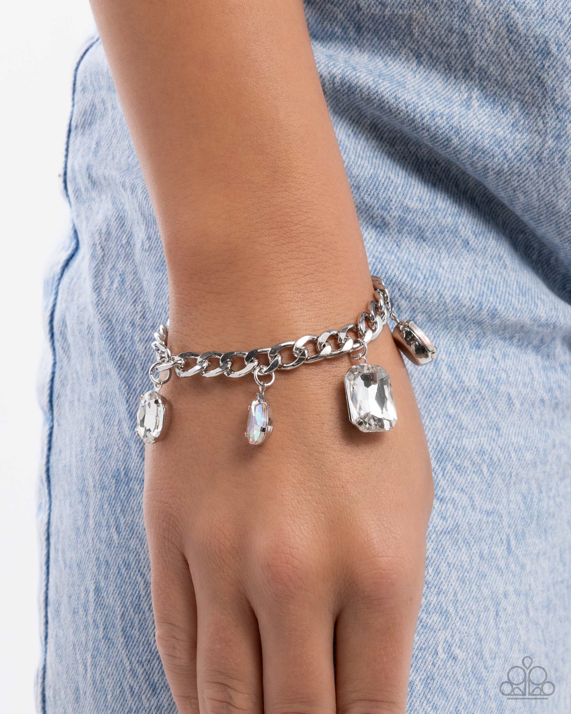 Silver chain bracelet with clear gemstones on a wrist against a denim background