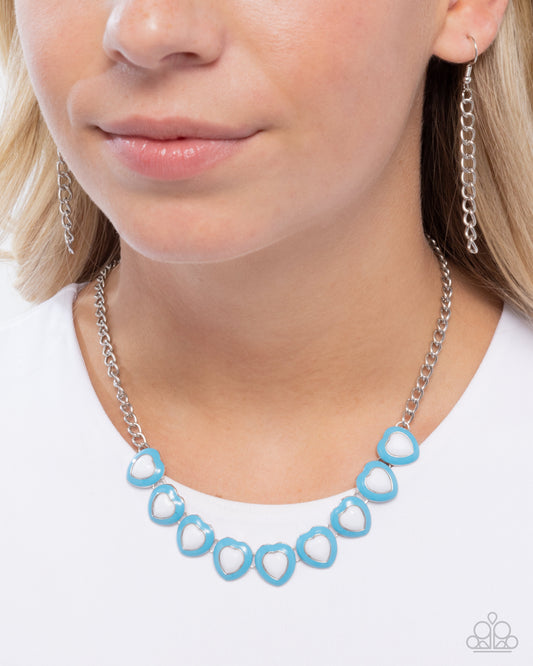 Person wearing a blue necklace and silver earrings on a white background